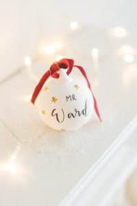 Handwritten personalised ceramic bauble with red velvet ribbon